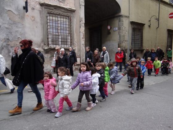 Un gruppo di bambini molto piccoli vanno a scuola a piedi accompagnati da un'adulta 
