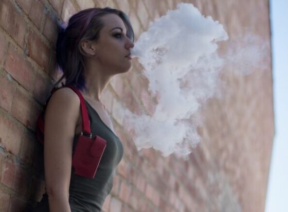 Una ragazza molto giovane fuma una sigaretta elettronica
