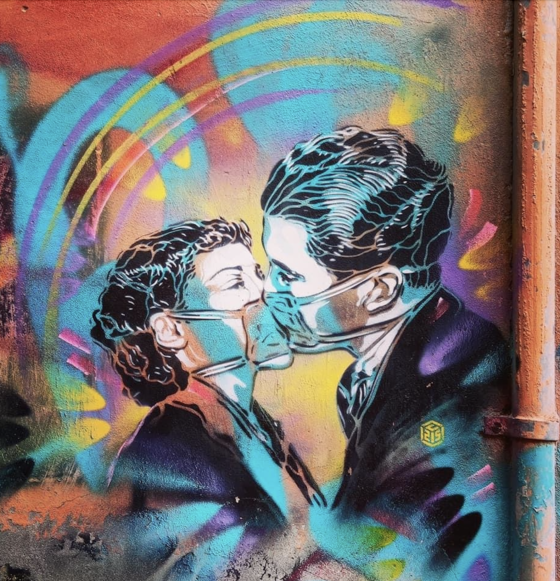 Una coppia con una mascherina si bacia. Opera dello street artist Christian Guémy, a Trastevere, Roma 