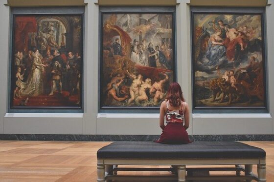 Una ragazza di spalle osserva alcuni quadri in un museo