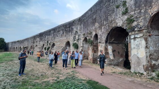 Un momento di un walkabout, con un gruppo di persone che attraversa un'antica cinta muraria romana