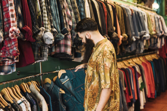 Un giovane sceglie degli abiti in un negozio dell'usato